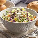 This quick and easy coleslaw is made with freshly shredded cabbage and carrots, all tossed in a creamy homemade dressing, making it the perfect addition for picnics and barbecues. With Memorial Day approaching, the season of summer picnics and backyard barbecues is about to kick off, and I have a variety of refreshing side dishes ready for cookouts, but I realized I was missing a classic favorite—coleslaw!